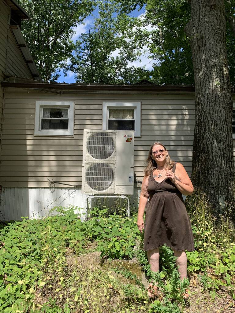 Debra Albro with the heat pump that replaced a coal-powered furnace, funded by carbon offsets from the Finger Lakes Climate Fund calculator.