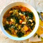 Bowl of soup with kale, carrots and white beans