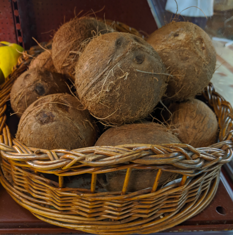 Coconuts are stacked in a wicker bowl.